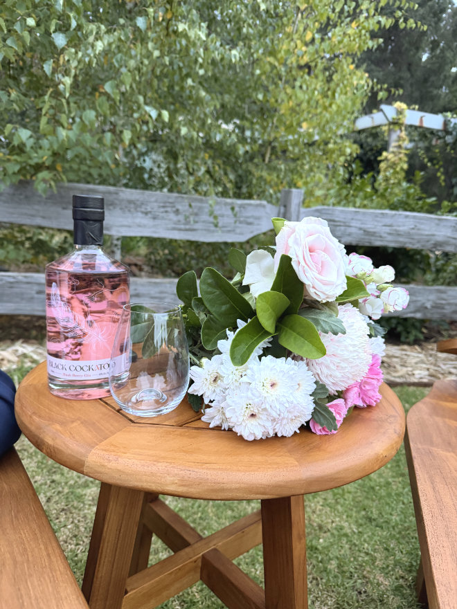 Black Cockatoo Distillery Bush Berry Gin and flower bouquet on a small wooden table in the Cellar Door garden.