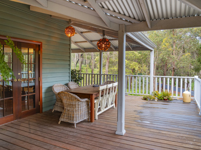 The veranda outdoor dining area at Stone's Throw Cottage in Bridgetown, with the forest surrounds.
