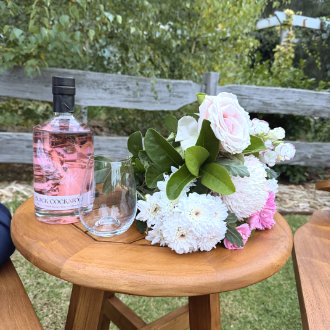 Black Cockatoo Distillery Bush Berry Gin and flower bouquet on a small wooden table in the Cellar Door garden.